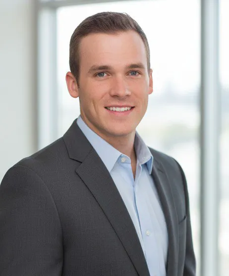 Dillon Bowen, studio headshot in a grey suit